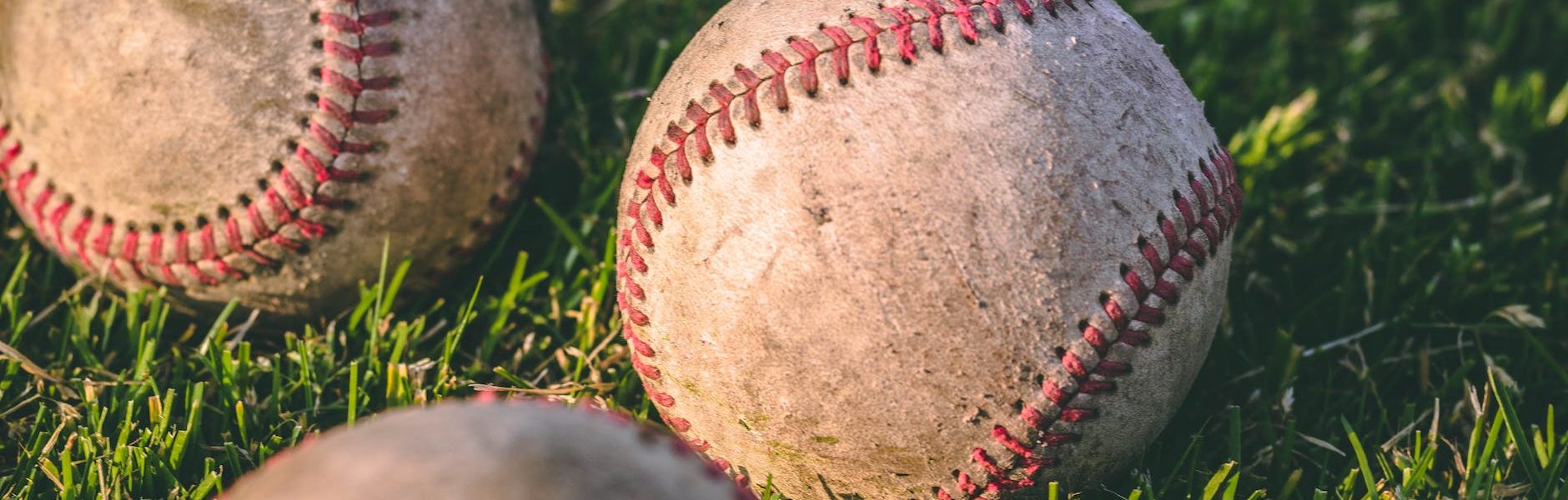 close up photography of four baseballs on green lawn grasses